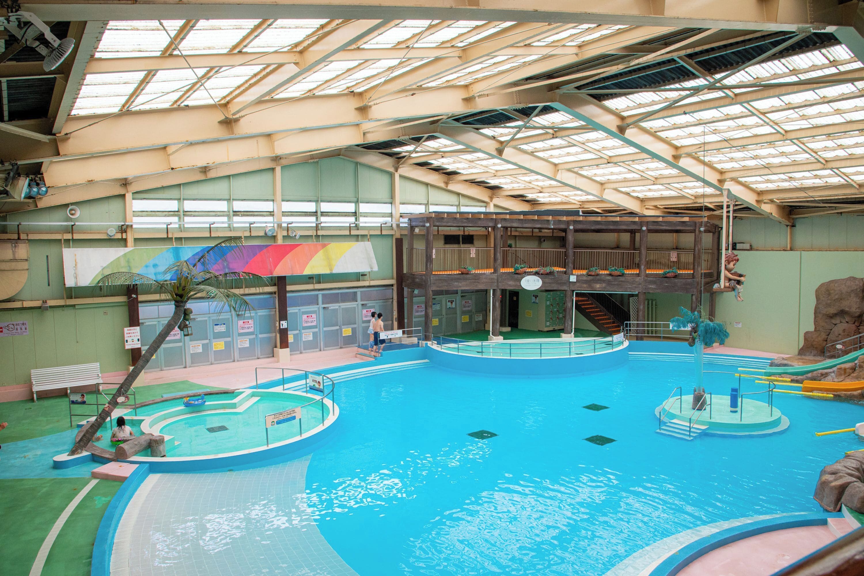 Une piscine intérieure dotée de plusieurs couloirs, d’un espace de jeux central et d’une structure de toit.