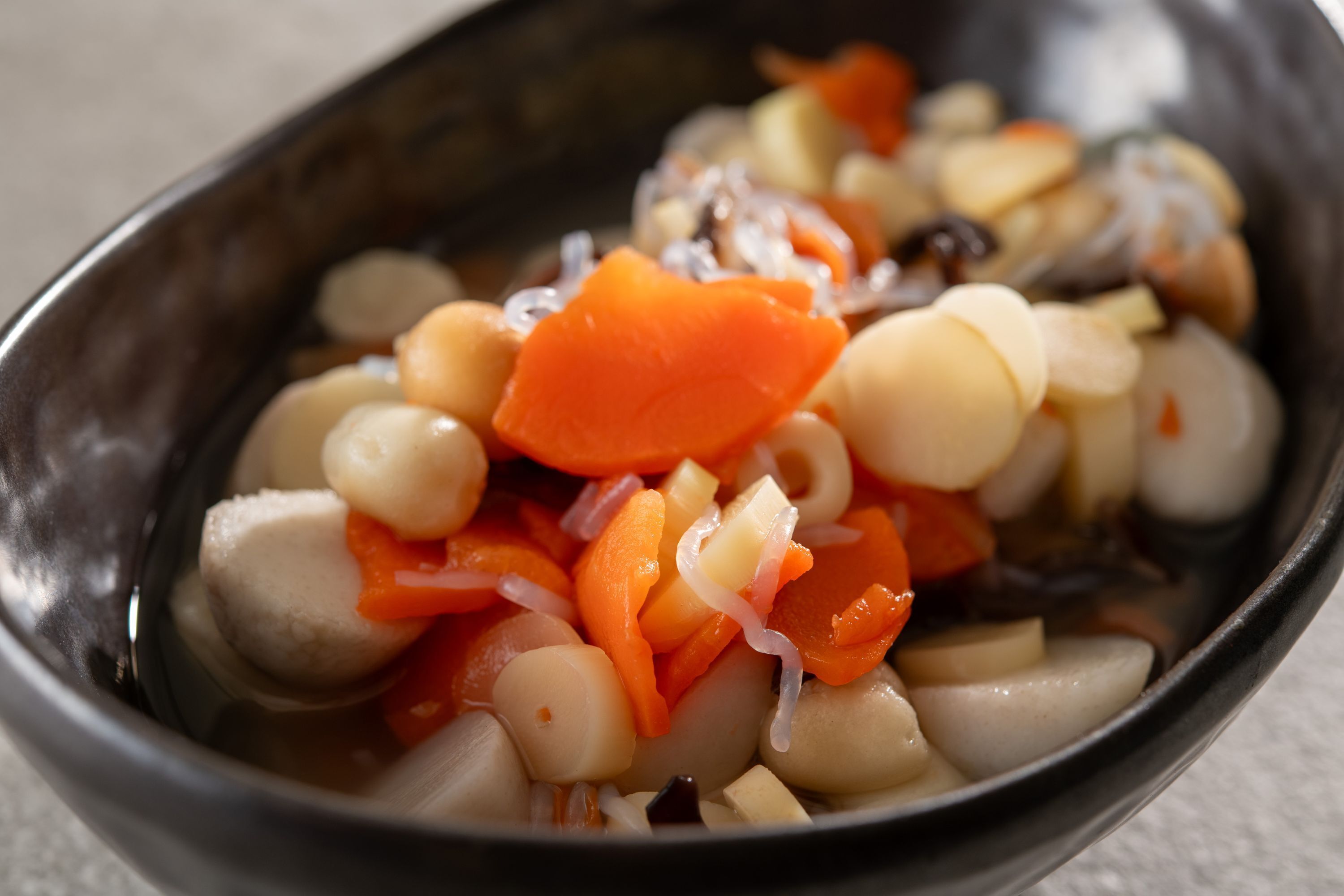 A bowl of mixed vegetables including carrots, onions, and white beans.