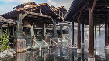 A traditional wooden structure with a stone foundation, wooden railings, and a clear water body in front.