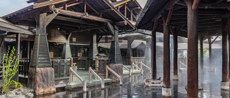 A traditional wooden structure with a stone foundation, wooden railings, and a clear water body in front.