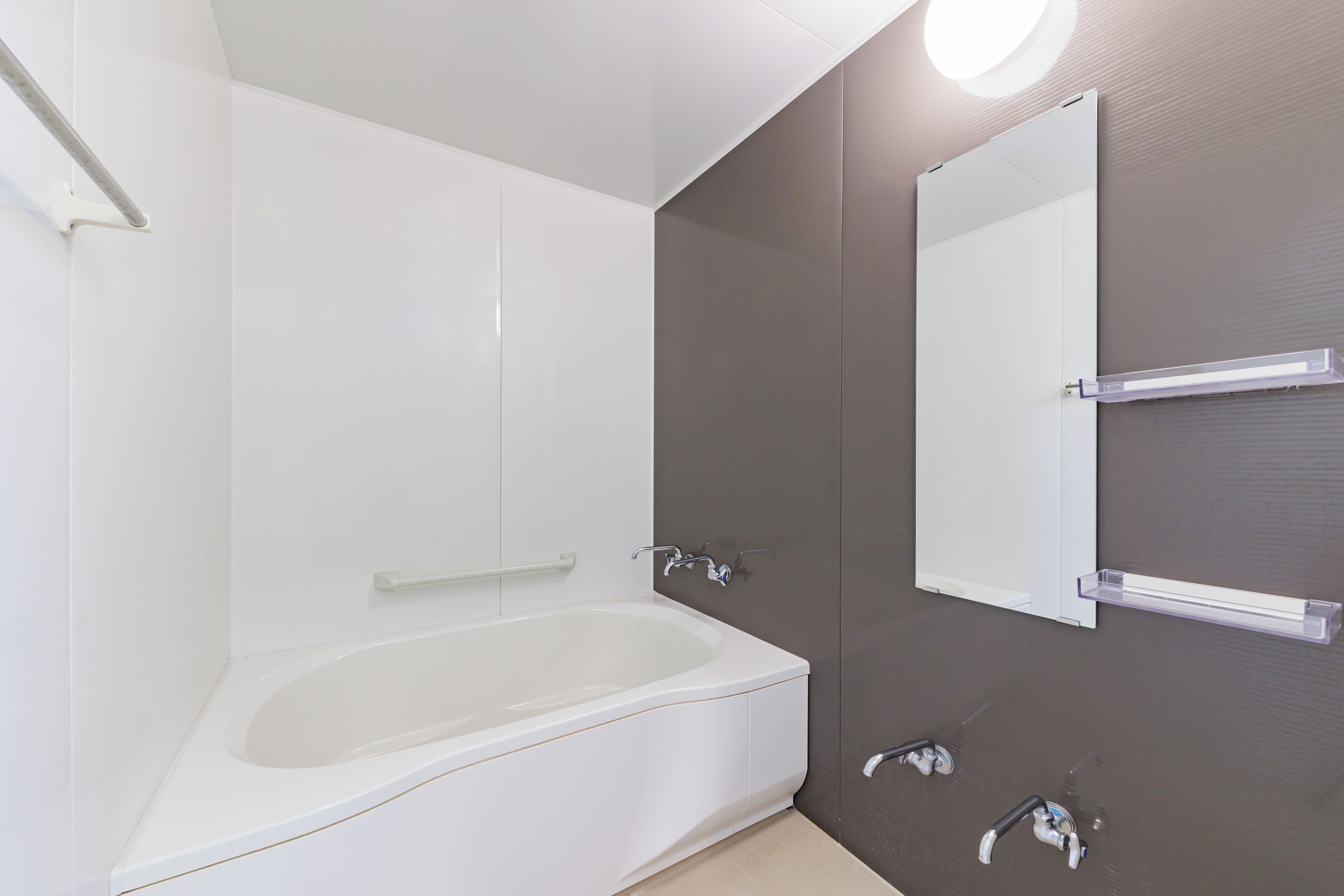 Een moderne badkamer met een vrijstaand bad, een spiegel aan de muur en een handdoekrek.