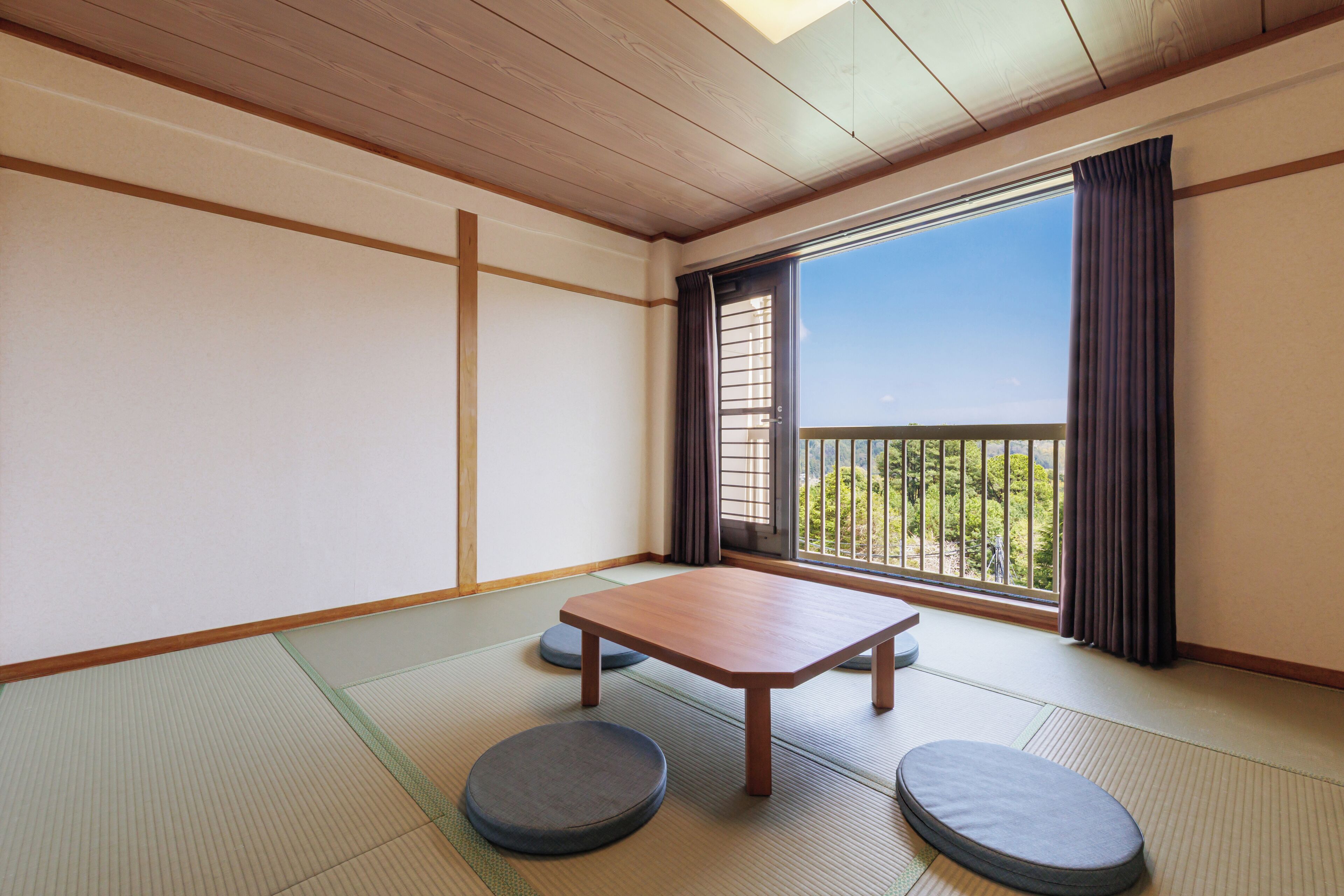 Ein traditioneller japanischer Raum mit Tatami-Böden, einem niedrigen Holztisch und Sitzkissen.