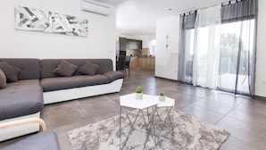 Een moderne woonkamer met een grijze bank, een witte salontafel en een pluizig grijs tapijt.