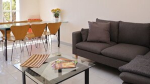 Una sala de estar moderna con un sofá, una mesa de centro de vidrio y un comedor con sillas y una mesa.
