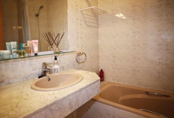A bathroom with a marble sink, a mirror, a shower, and a towel rack.