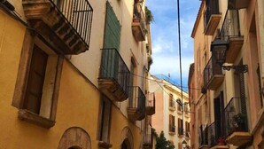 Una calle estrecha bordeada por edificios con balcones y arcos.