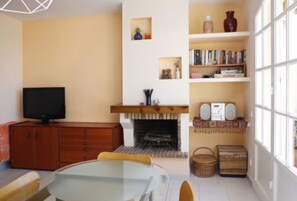 A living room with a fireplace, television, and bookshelves.