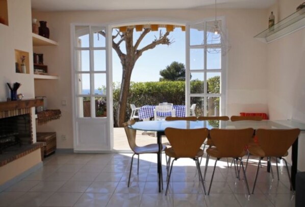 A dining area with a table and chairs, a fireplace, and a view of the outdoors through large windows.