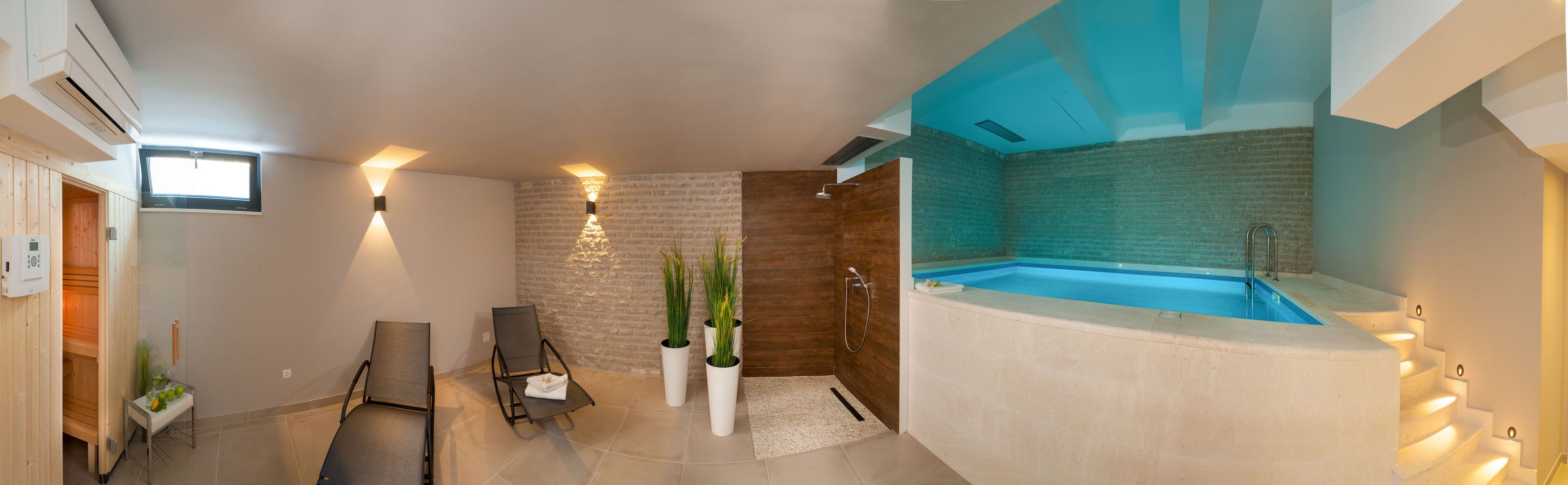 A modern bathroom with a built-in jacuzzi, wooden walls, and two lounge chairs.