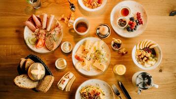 Un bufé de desayuno con diversos platos, entre ellos pan, queso y frutas, dispuesto sobre una mesa de madera.