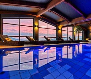 A pool area with lounge chairs and large windows. - Natura Hotel Bodenmais (Bodenmais)