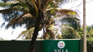 Señal de Villa Whispering Shells, con una palmera y un aplique esférico en primer plano.