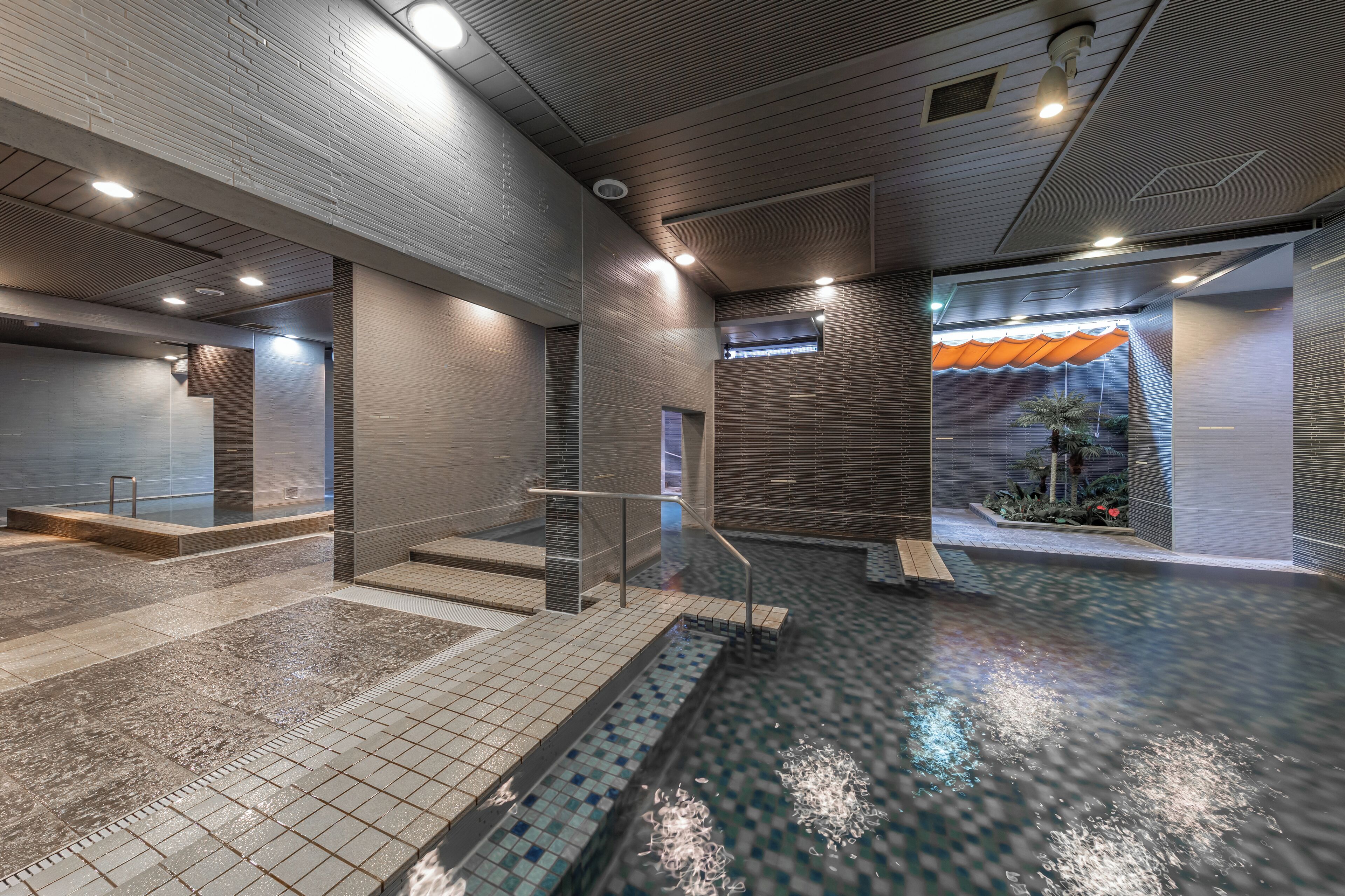 A modern indoor pool area with a tiled floor, a small pool, and a staircase leading to a higher level.
