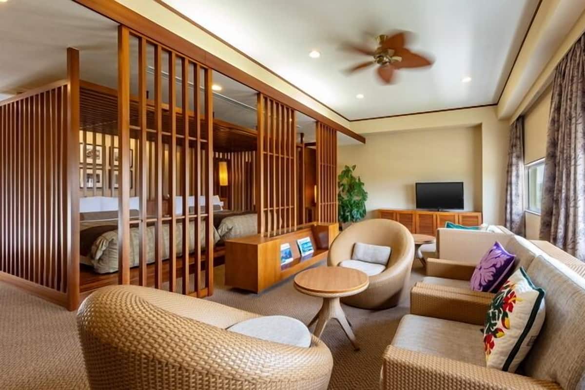 A hotel room with a seating area, a television, and a large window.
