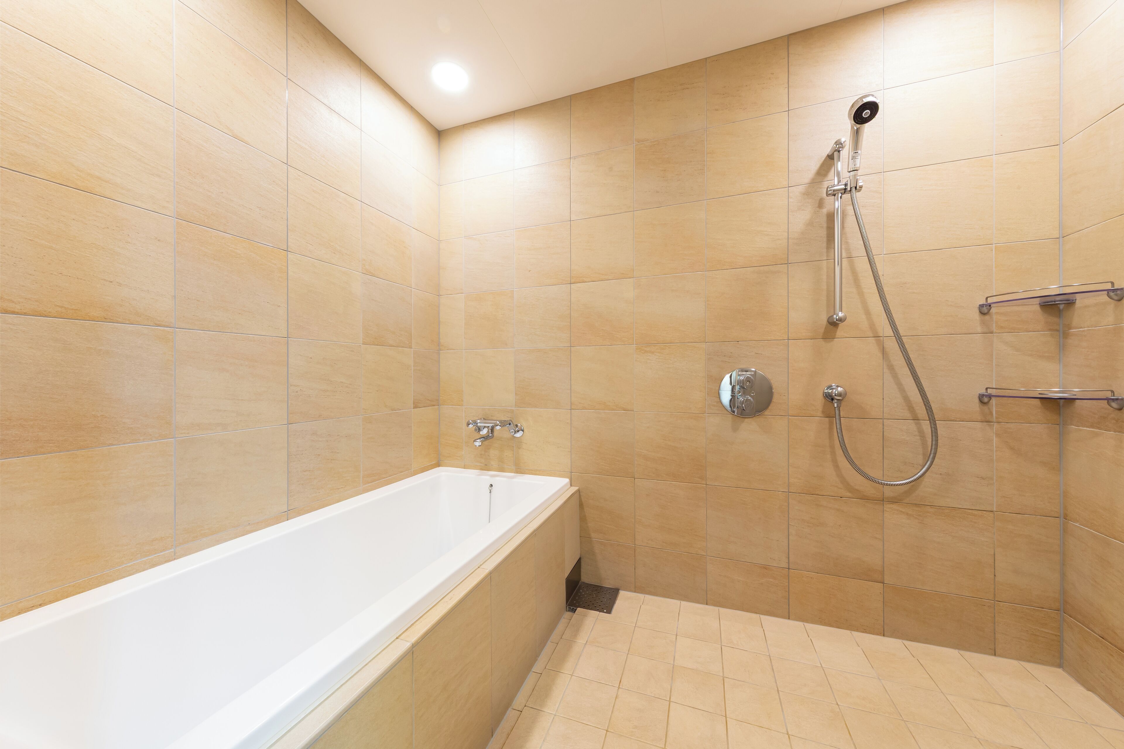 A modern bathroom with a bathtub, shower, and tiled walls.