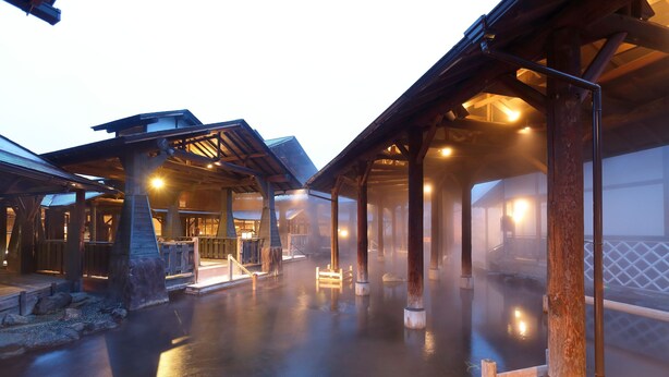 A traditional wooden building with a covered outdoor area and a hot spring.