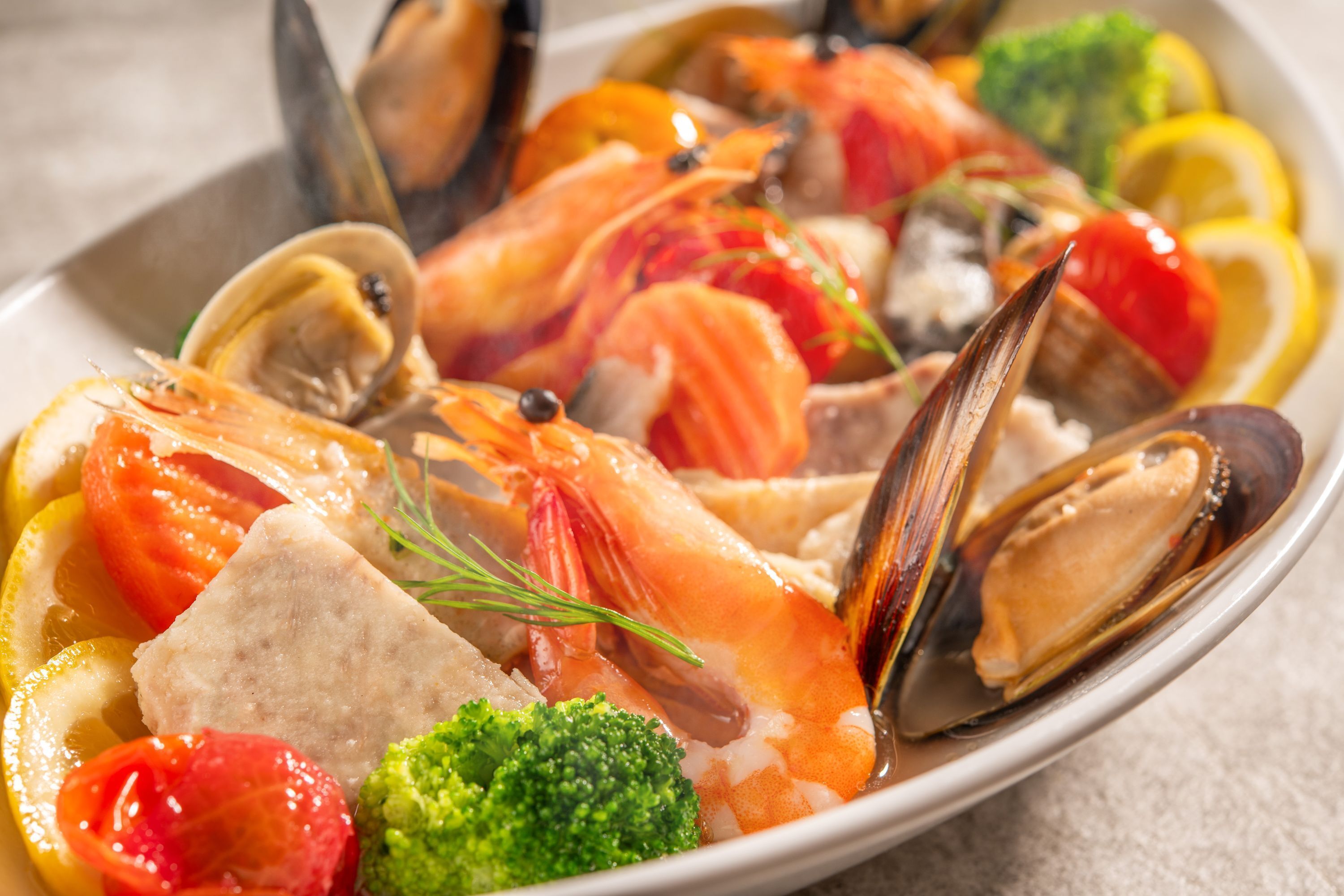 Un piatto di pesce con gamberi, cozze e verdure.