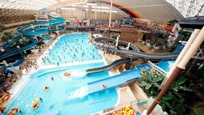An indoor water park with multiple pools, slides, and a large covered area.