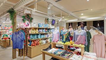 Un magasin de vêtements où sont exposés différents types de vêtements, notamment des chemises et des robes.