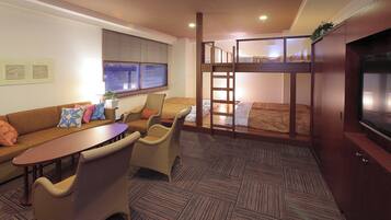 A compact hotel room with a bunk bed, a sofa, a dining table, and a TV.