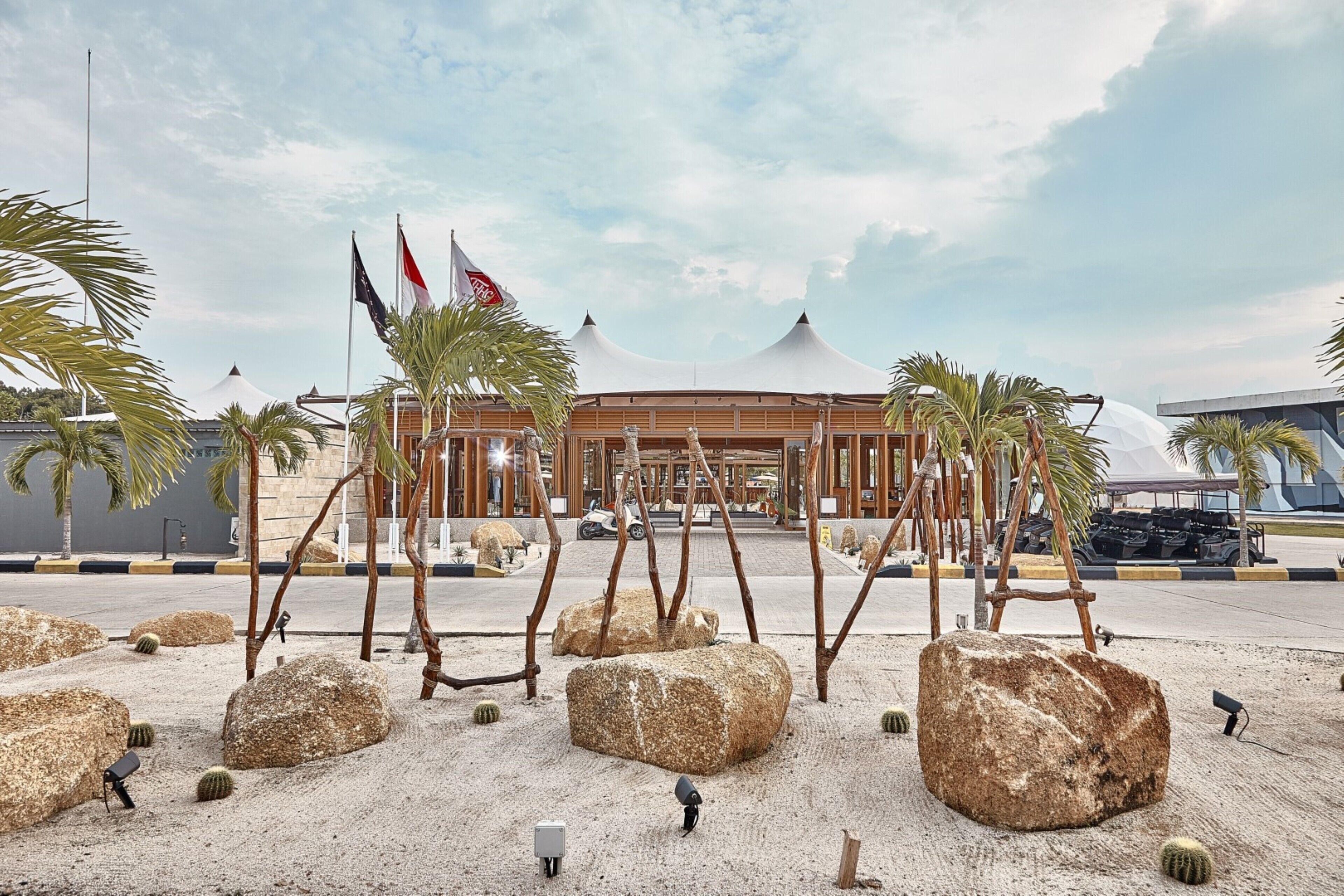 A building with a modern design, featuring a large open space with palm trees and rocks.