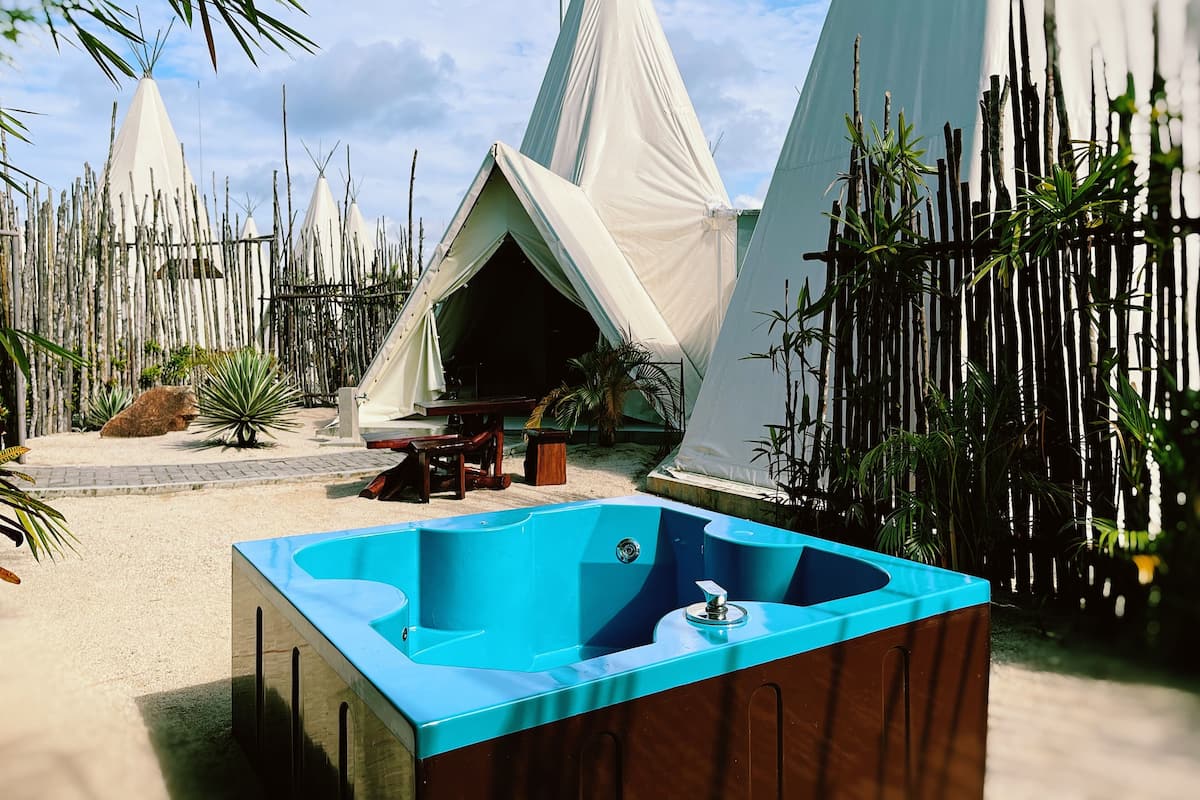 A series of white tents with a blue jacuzzi in the foreground.