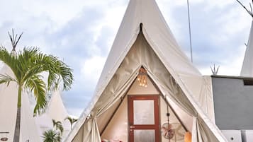 Un hébergement de style tipi, doté d’une porte centrale, d’un coin salon avec des coussins et d’une petite table.