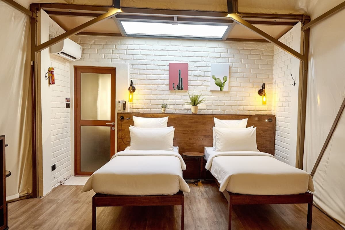 A room with two beds, a wooden headboard, a white brick wall, and a skylight.