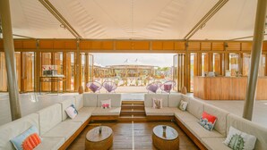 A spacious outdoor seating area with wooden furniture and a view of the beach. - The ANMON Resort Bintan- Glamping (Bintan)