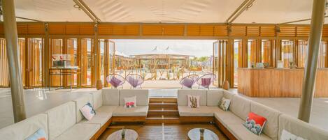 Un vaste espace extérieur aménagé avec du mobilier en bois et offrant une vue sur la plage.