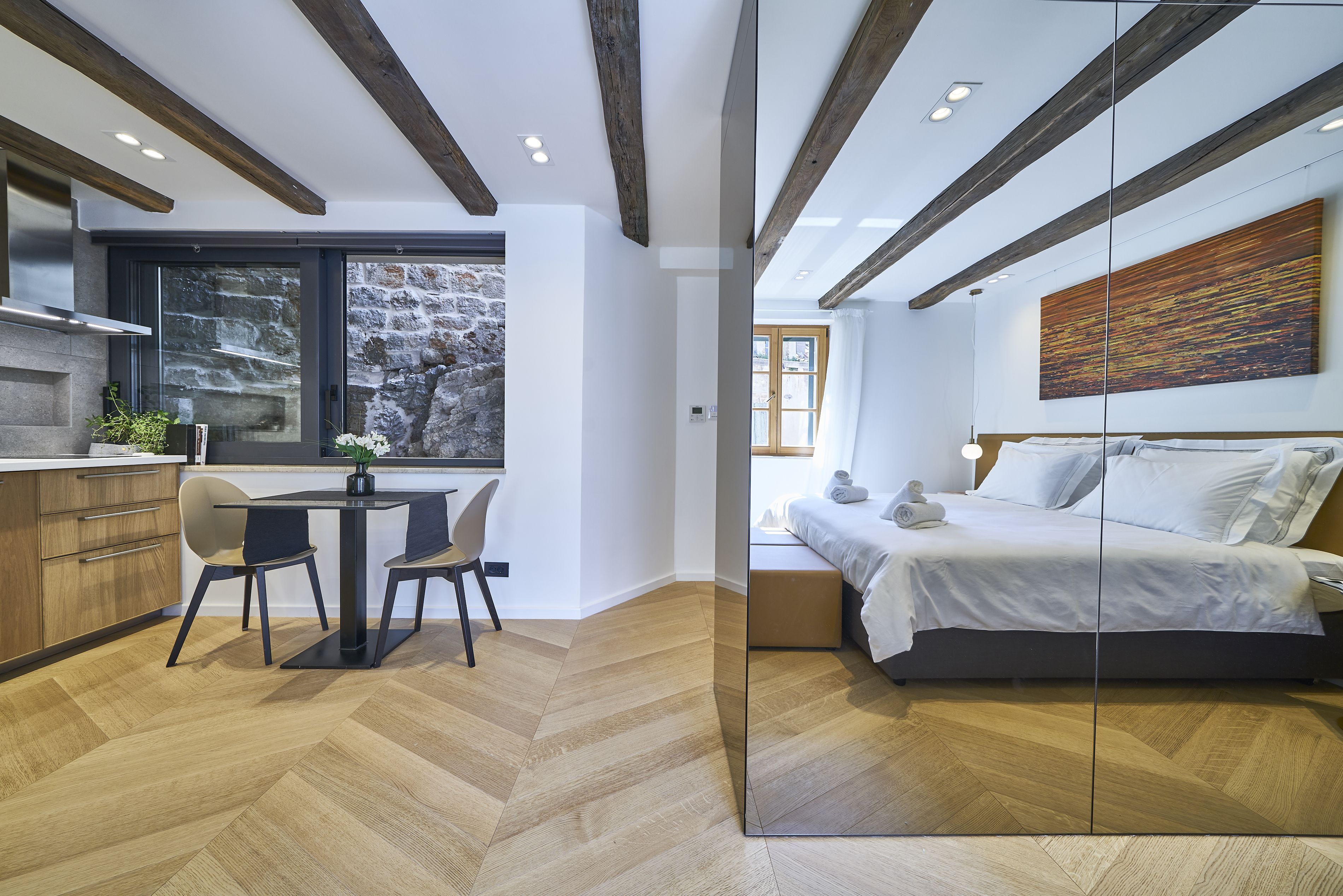 Un dormitorio moderno con una cama grande, suelo de madera y pared de piedra.
