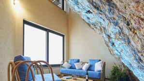 A room with a herringbone-patterned floor, a wooden bench, a blue sofa, and a large window. - Villa Pergola (Sibenik)