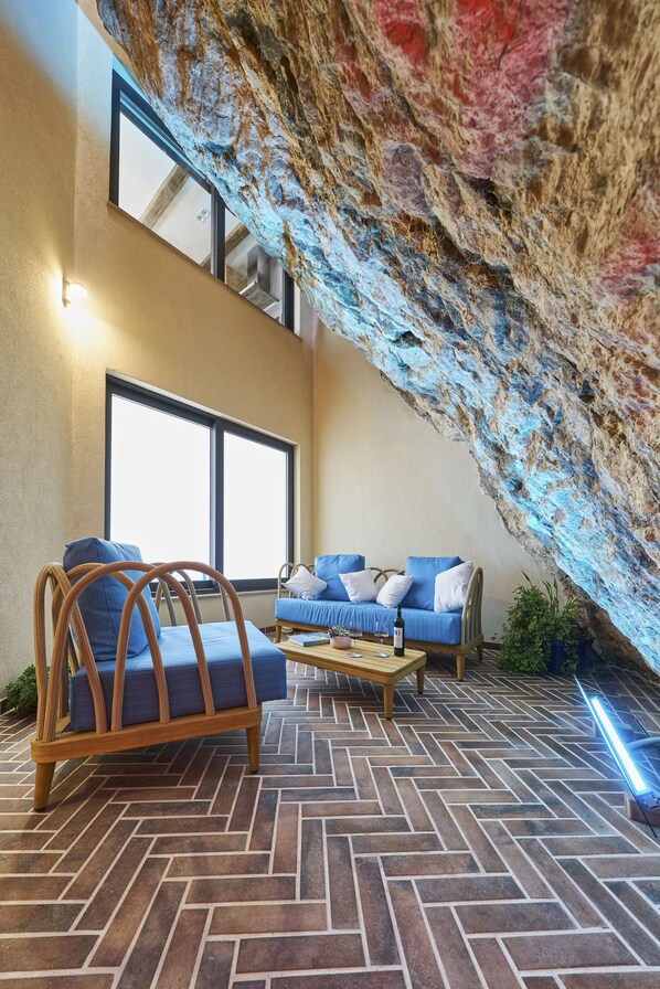 A room with a herringbone-patterned floor, a wooden bench, a blue sofa, and a large window. - Villa Pergola (Sibenik)