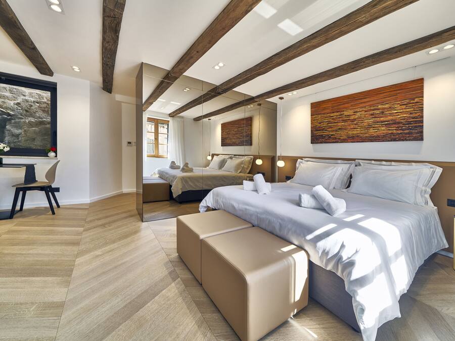 A modern bedroom with a large bed, a desk, and a view of the outdoors.