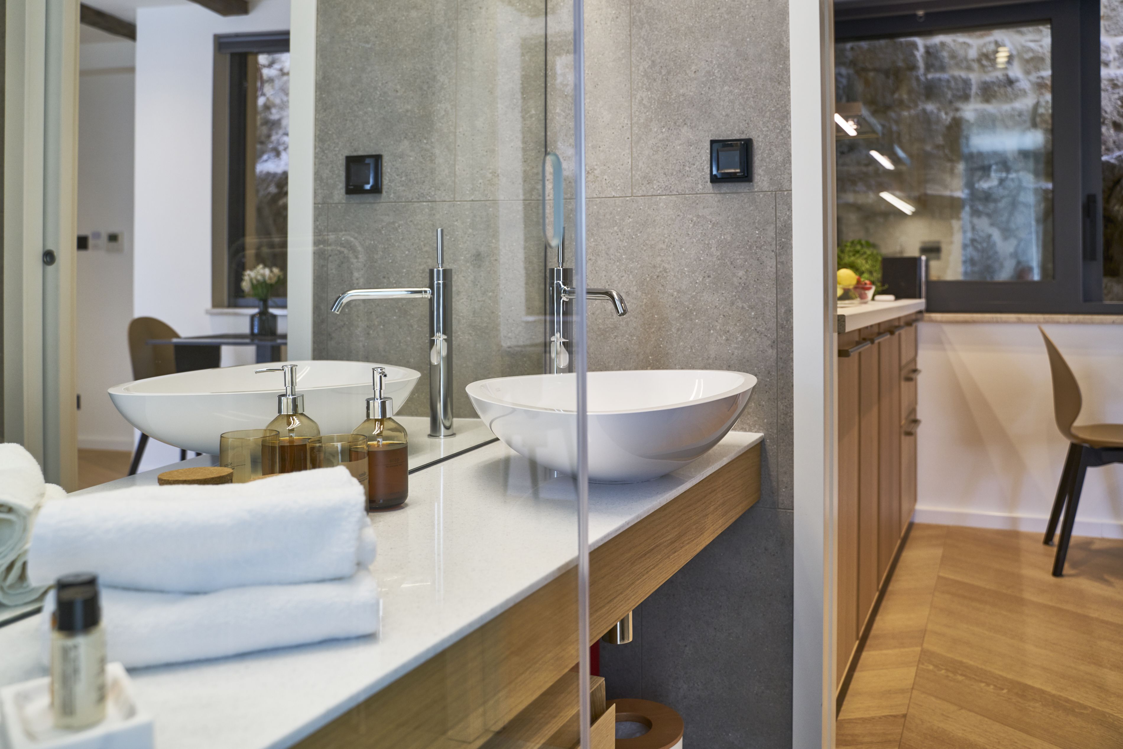A modern bathroom with two large sinks, a mirror, and a wooden vanity.