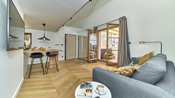 Departamento Deluxe, vista al mar | Área de sala de estar | Televisión de pantalla plana y piso con calefacción