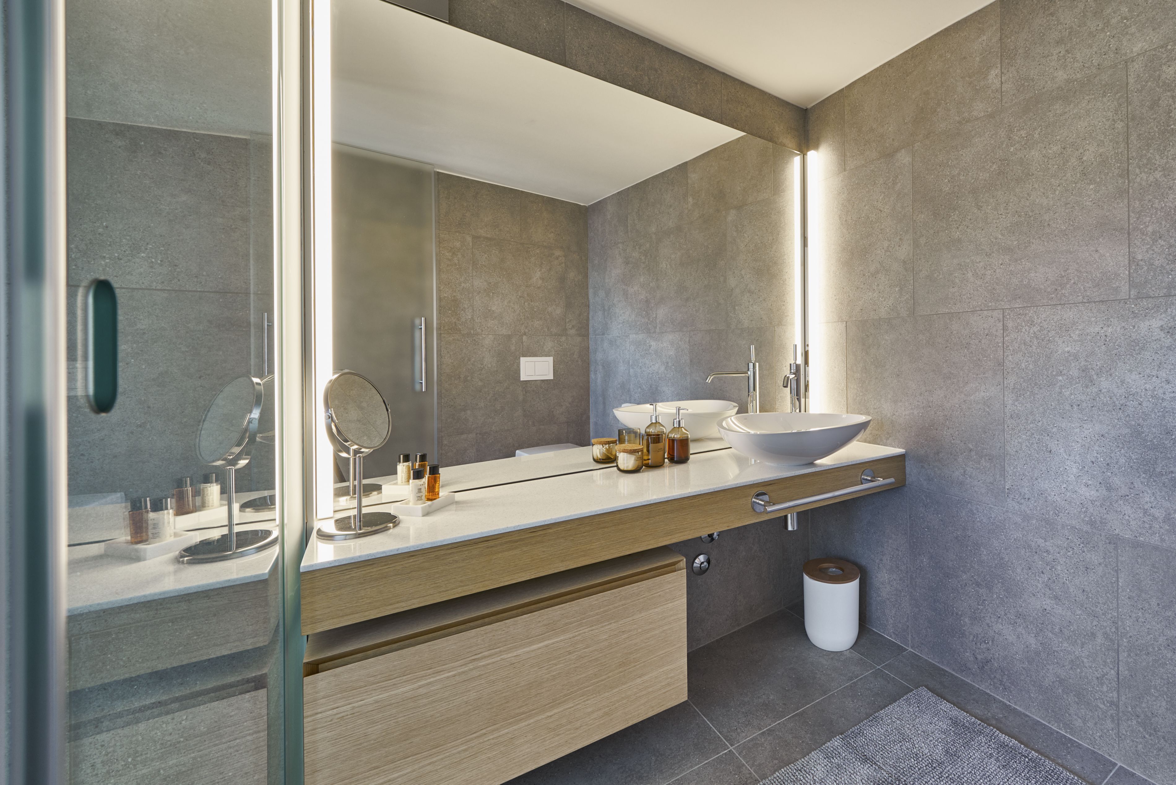 A modern bathroom with a large mirror, a vessel sink, and a wooden vanity.