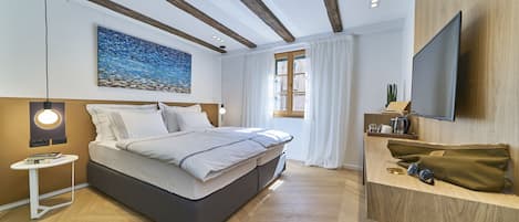 Un dormitorio moderno con cama, mesita de noche y televisor montado en la pared.