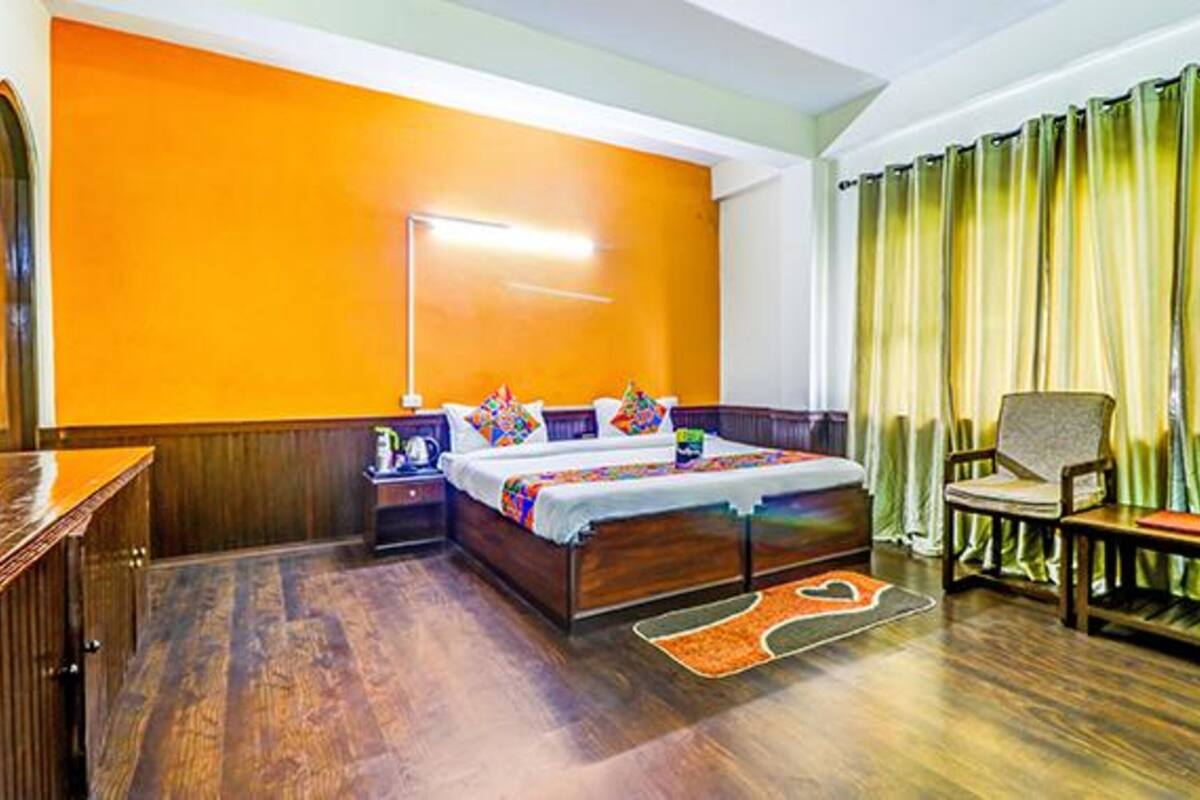 A hotel room with a wooden bed, a nightstand, a chair, and a desk.