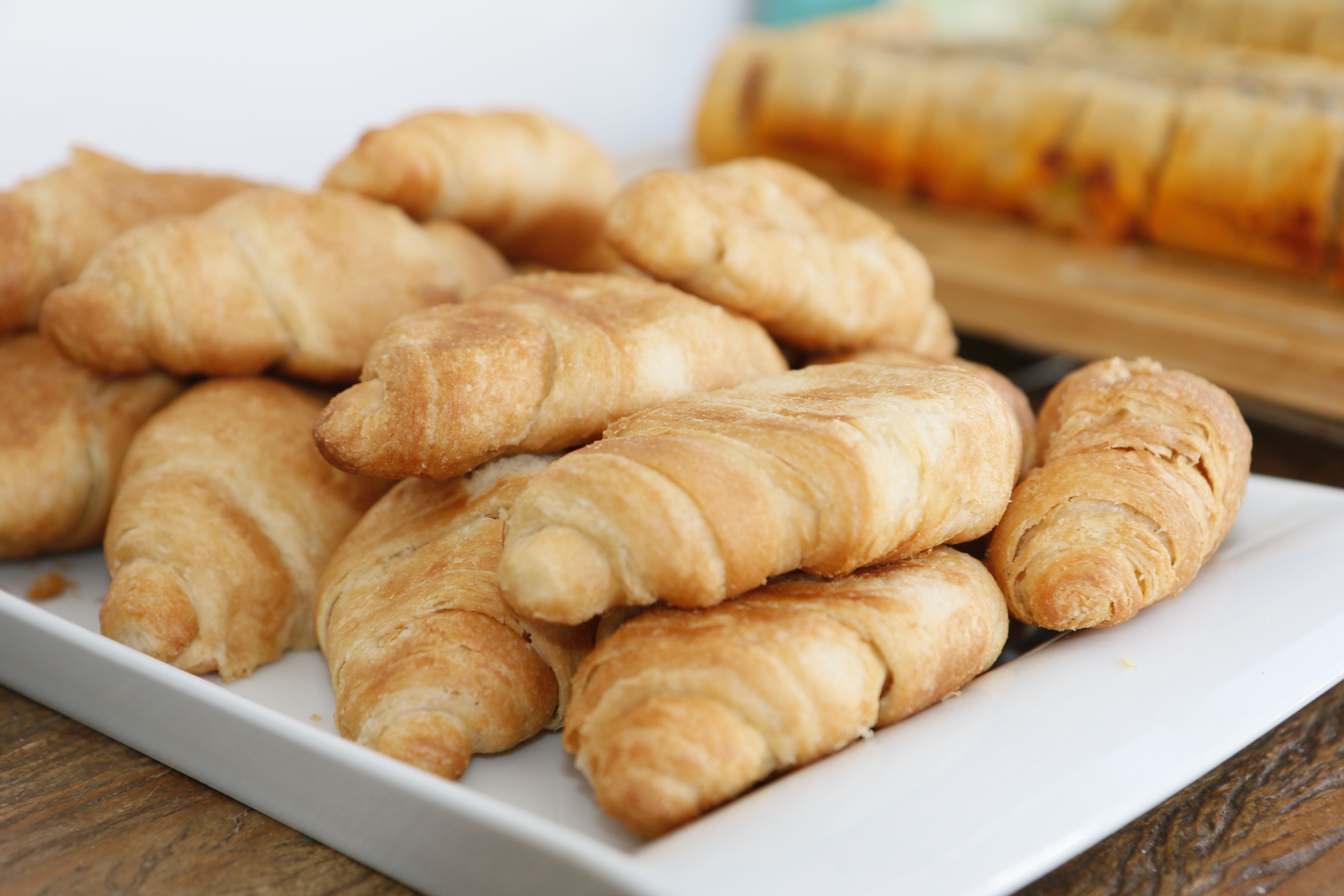 A white plate with several golden-brown croissants.