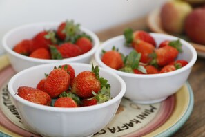 Tres tazones blancos llenos de fresas sobre un plato colorido.