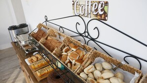 A buffet table with various baked goods and a coffee sign. - Pousada Conca di Mare (Bertioga)