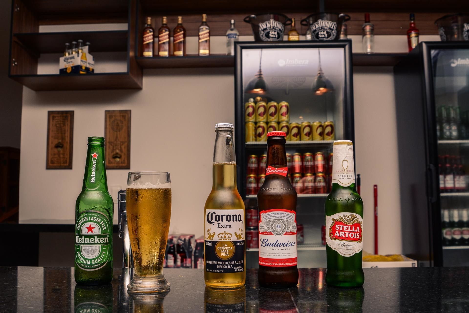 Een bargedeelte met verschillende bierflesjes en een glas bier.