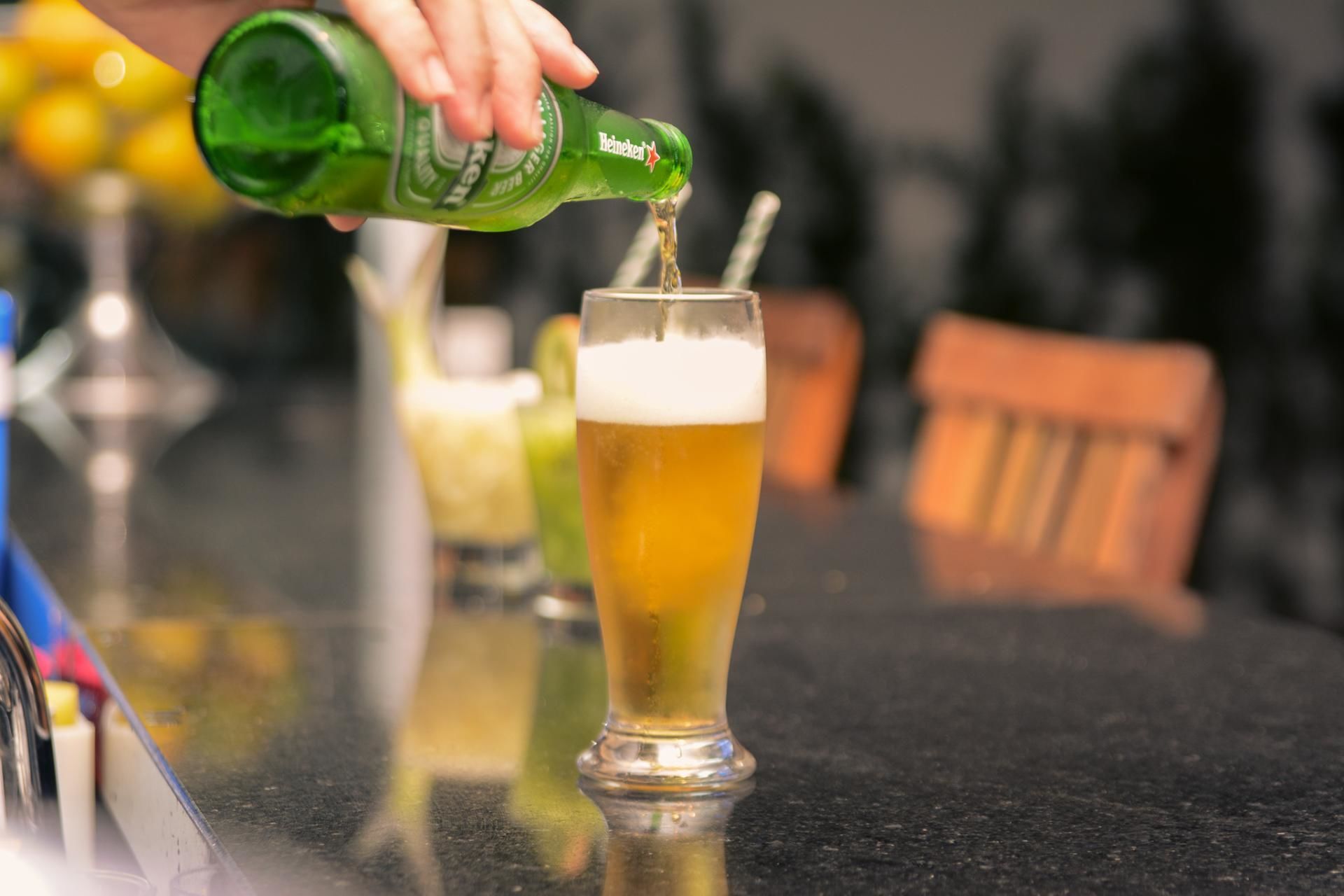 A person pouring beer into a glass with a straw.
