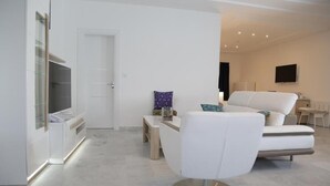 Una sala de estar moderna con un sofá blanco, una mesita de centro y un televisor.