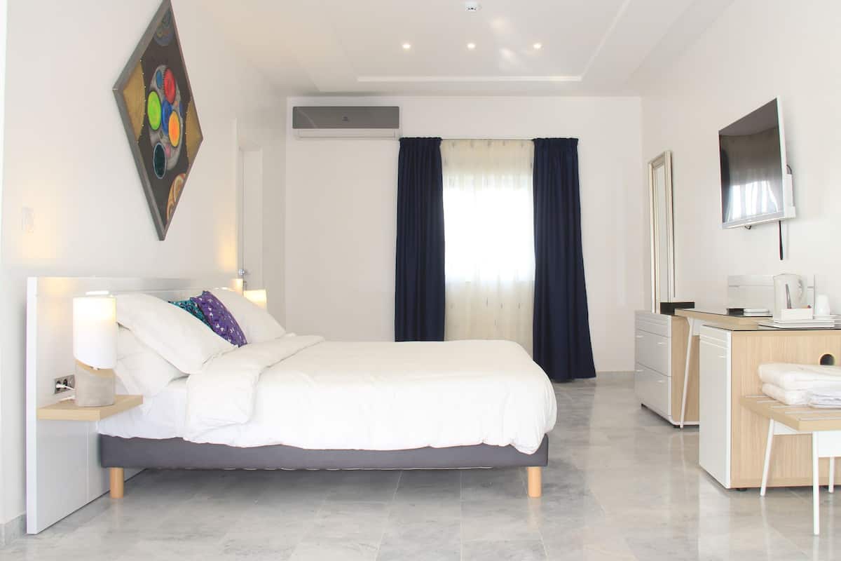 A modern hotel room with a bed, desk, chair, and a TV.