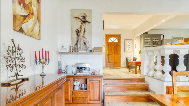 Amplia sala de estar con escalera de madera, una cafetera y un candelabro decorativo de metal.