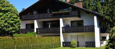 A two-story building with balconies, a satellite dish, and a well-maintained lawn.