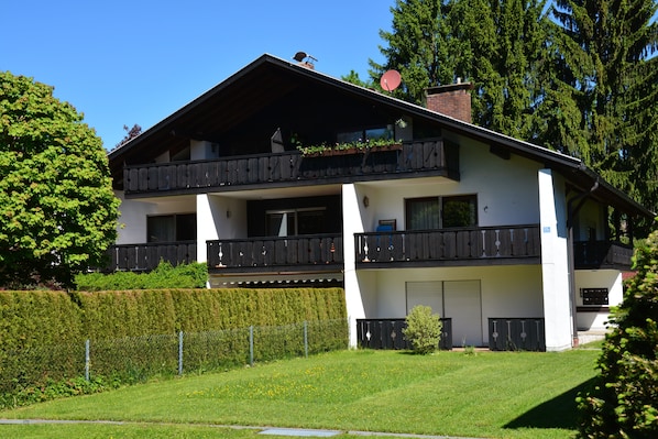A two-story building with balconies, a satellite dish, and a well-maintained lawn.