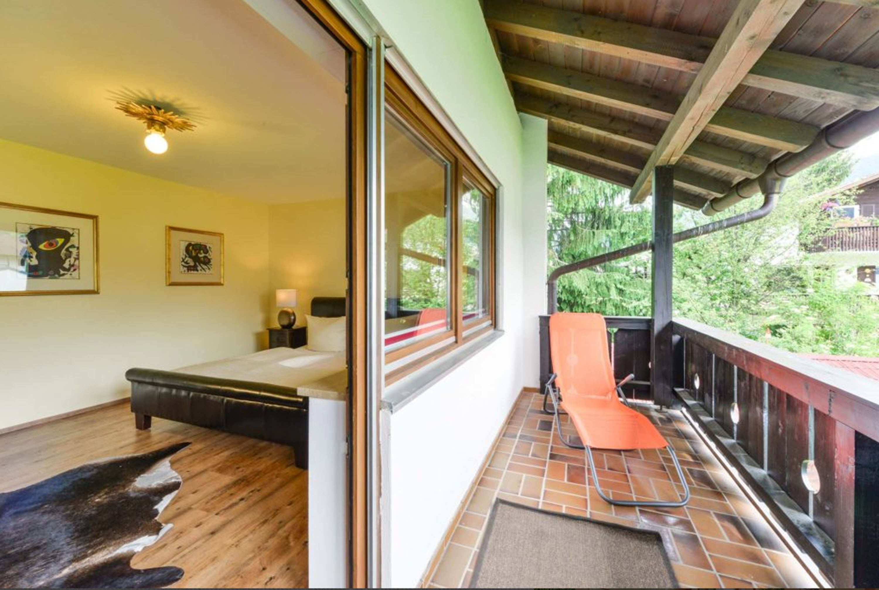 Una habitación con cama, ventana, silla y vista a zonas verdes.